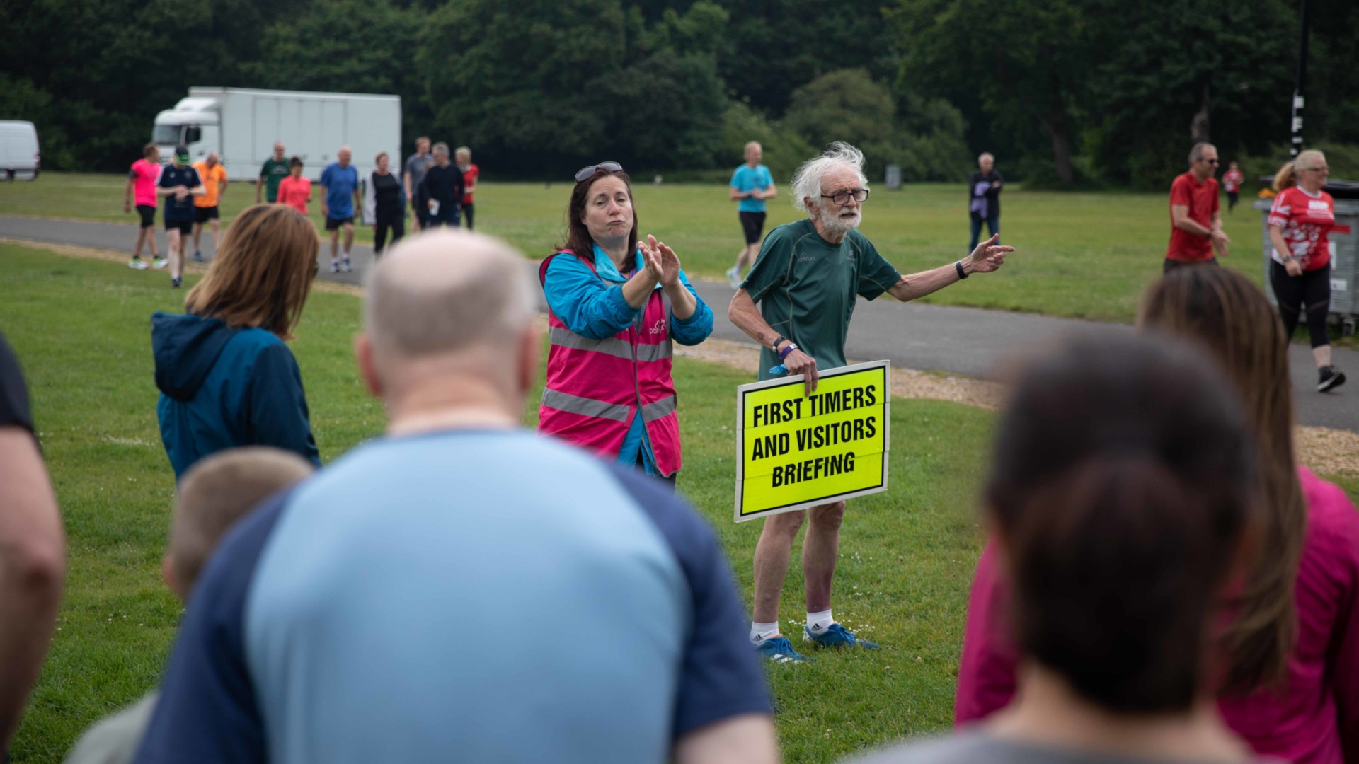 Old man with yellow sign "First timers and visitor briefing"